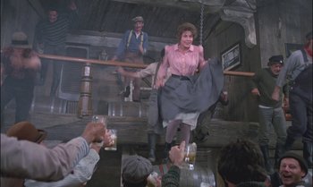 Movie still from “Pete's Dragon” (1977), directed by Don Chaffey – A group of people standing in a room with beer; Wide shot, Low angle