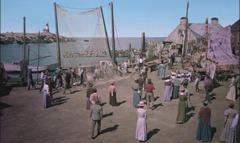 Movie still from “Pete's Dragon” (1977), directed by Don Chaffey – A group of people standing on top of a sandy beach; Extreme Wide shot, High angle