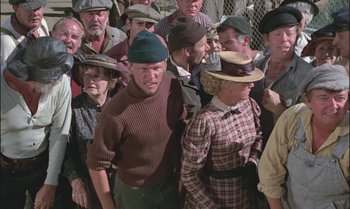 Movie still from “Pete's Dragon” (1977), directed by Don Chaffey – A group of people standing around each other wearing hats; Medium shot, High angle