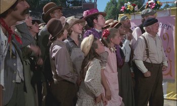 Movie still from “Pete's Dragon” (1977), directed by Don Chaffey – A group of people standing next to each other on a field; Medium shot, Low angle