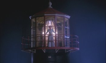 Movie still from “Pete's Dragon” (1977), directed by Don Chaffey – A woman standing inside a light house at night; Extreme Wide shot, Low angle
