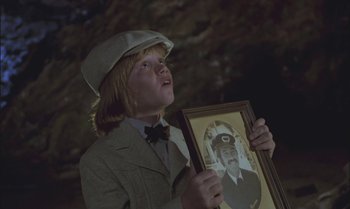 Movie still from “Pete's Dragon” (1977), directed by Don Chaffey – A young boy holding a picture of a man in a hat; Close Up shot, Low angle