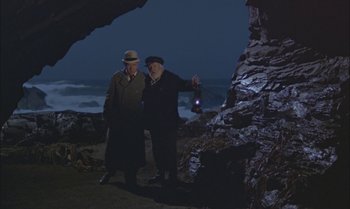 Movie still from “Pete's Dragon” (1977), directed by Don Chaffey – Two men standing next to each other on the beach; Wide shot, High angle