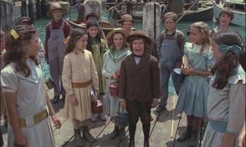 Movie still from “Pete's Dragon” (1977), directed by Don Chaffey – A group of people standing on a dock; Medium shot, High angle
