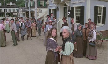 Movie still from “Pete's Dragon” (1977), directed by Don Chaffey – A group of people standing in front of a building; Wide shot, High angle