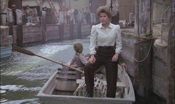 Movie still from “Pete's Dragon” (1977), directed by Don Chaffey – A woman sitting in a boat on a body of water; Wide shot, High angle