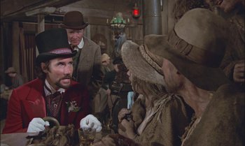 Movie still from “Pete's Dragon” (1977), directed by Don Chaffey – A group of men in a room with hats on; Medium shot, Over the shoulder angle