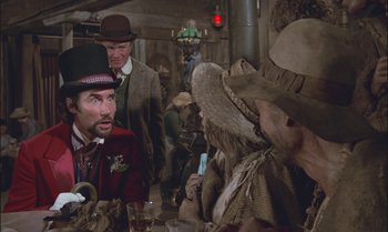 Movie still from “Pete's Dragon” (1977), directed by Don Chaffey – A group of people sitting around a table; Medium shot, Over the shoulder angle