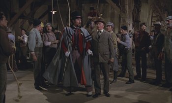 Movie still from “Pete's Dragon” (1977), directed by Don Chaffey – A group of men standing next to each other in a room; Wide shot, Low angle