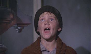 Movie still from “Pete's Dragon” (1977), directed by Don Chaffey – A young boy wearing a sweater and a hat is looking up; Close Up shot, Low angle