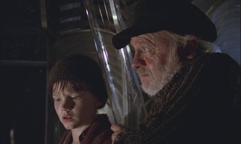 Movie still from “Pete's Dragon” (1977), directed by Don Chaffey – An older man and a young boy are standing next to each other; Close Up shot, Low angle