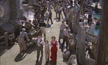 Movie still from “Pete's Dragon” (1977), directed by Don Chaffey – A group of people walking down a street; Wide shot, High angle