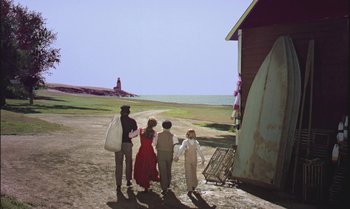 Movie still from “Pete's Dragon” (1977), directed by Don Chaffey – A group of people standing next to each other on a dirt field; Wide shot, High angle
