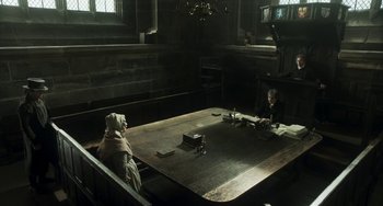 Movie still from “Peterloo” (2018), directed by Mike Leigh – Two people sitting at a wooden table in a dark room; Wide shot, High angle