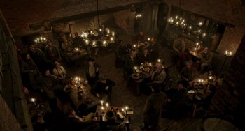 Movie still from “Peterloo” (2018), directed by Mike Leigh – A group of people sitting around a table with lit candles; Extreme Wide shot, High angle