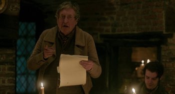 Movie still from “Peterloo” (2018), directed by Mike Leigh – An older man holding a paper in a dimly - lit room; Medium shot, Over the shoulder angle