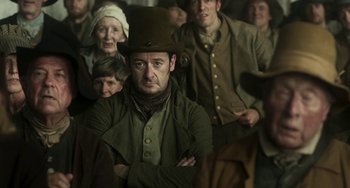 Movie still from “Peterloo” (2018), directed by Mike Leigh – A group of people standing around a man in a hat; Medium shot, Over the shoulder angle