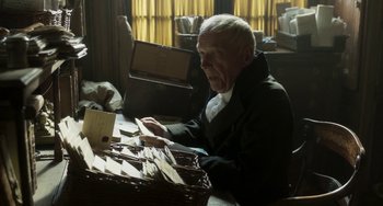 Movie still from “Peterloo” (2018), directed by Mike Leigh – An older man sitting at a table with papers; Medium shot, High angle