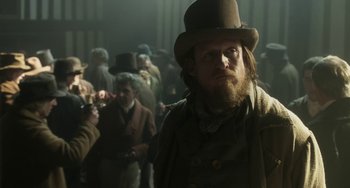 Movie still from “Peterloo” (2018), directed by Mike Leigh – A man with a long beard wearing a hat; Medium shot, Over the shoulder angle