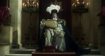 Movie still from “Peterloo” (2018), directed by Mike Leigh – A man sitting on top of a chair in a room; Medium shot, Low angle