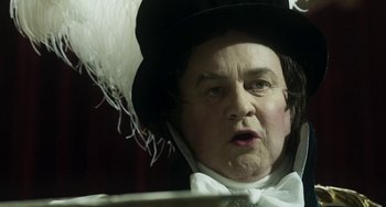 Movie still from “Peterloo” (2018), directed by Mike Leigh – An old man wearing a black hat and a white bow tie; Close Up shot, Low angle
