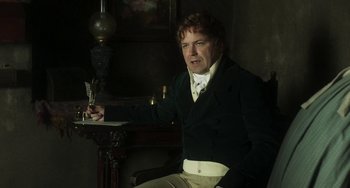 Movie still from “Peterloo” (2018), directed by Mike Leigh – A man sitting in a chair holding a pen; Medium shot, High angle