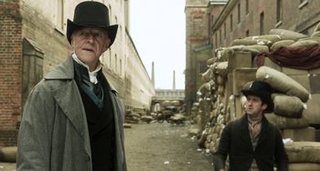 Movie still from “Peterloo” (2018), directed by Mike Leigh – A man and a woman dressed in period clothing standing in an alley; Medium shot, Over the shoulder angle