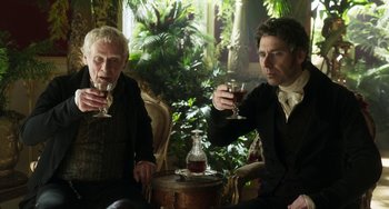 Movie still from “Peterloo” (2018), directed by Mike Leigh – Two men sitting next to each other holding wine glasses; Medium shot, Over the shoulder angle