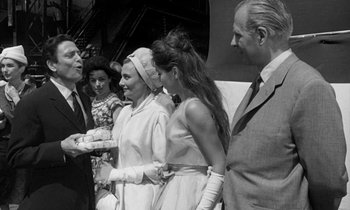Movie still from “Phaedra” (1962), directed by Jules Dassin – A group of people standing next to each other on a field; Medium shot, Over the shoulder angle