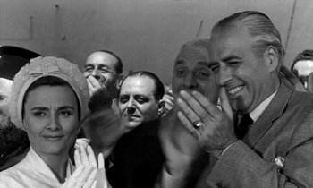 Movie still from “Phaedra” (1962), directed by Jules Dassin – A black and white photo of a group of men and a woman; Medium shot, High angle