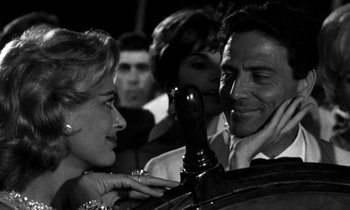 Movie still from “Phaedra” (1962), directed by Jules Dassin – A man and a woman looking at each other in front of other people; Close Up shot, Over the shoulder angle