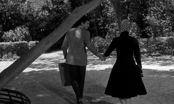 Movie still from “Phaedra” (1962), directed by Jules Dassin – A man and a woman holding hands while holding hands; Medium shot, High angle