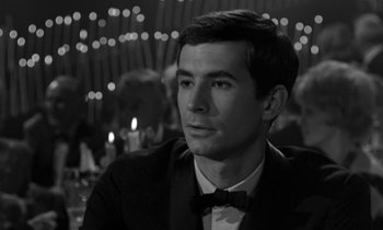 Movie still from “Phaedra” (1962), directed by Jules Dassin – Black and white photograph of a man wearing a bow tie; Close Up shot, Over the shoulder angle