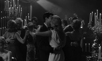 Movie still from “Phaedra” (1962), directed by Jules Dassin – A man and a woman dancing in front of a crowd; Medium shot, Low angle