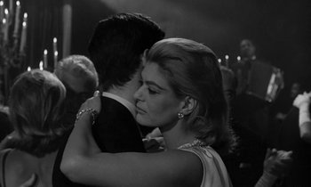 Movie still from “Phaedra” (1962), directed by Jules Dassin – A man and a woman hugging each other in front of a crowd of onlookers; Close Up shot, Over the shoulder angle