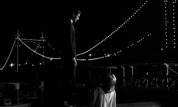 Movie still from “Phaedra” (1962), directed by Jules Dassin – A man standing on a skateboard in front of a woman; Wide shot, Low angle