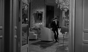 Movie still from “Phaedra” (1962), directed by Jules Dassin – A black and white photo of a man in a suit and tie; Wide shot, High angle