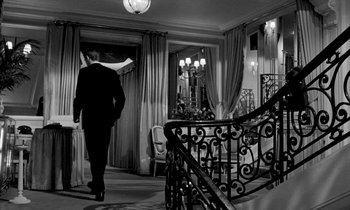 Movie still from “Phaedra” (1962), directed by Jules Dassin – A black and white photo of a man in a suit; Wide shot, Low angle