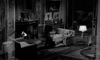 Movie still from “Phaedra” (1962), directed by Jules Dassin – A man laying on a couch in a living room; Wide shot, High angle