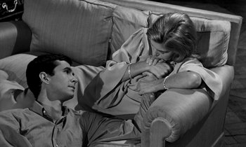 Movie still from “Phaedra” (1962), directed by Jules Dassin – A man and a woman laying on a couch; Medium shot, High angle