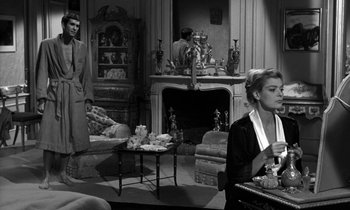 Movie still from “Phaedra” (1962), directed by Jules Dassin – A man and a woman are sitting in a living room; Medium shot, Over the shoulder angle