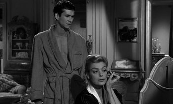 Movie still from “Phaedra” (1962), directed by Jules Dassin – A man and a woman are standing in a living room; Medium shot, Over the shoulder angle