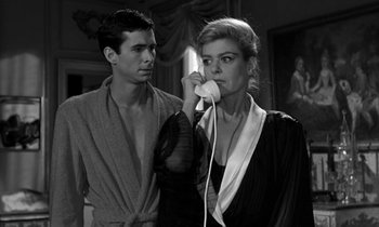 Movie still from “Phaedra” (1962), directed by Jules Dassin – A man and a woman standing next to each other holding a phone; Medium shot, Low angle