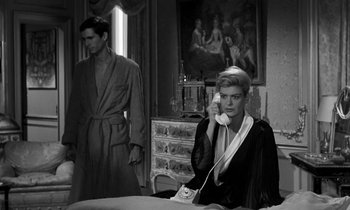 Movie still from “Phaedra” (1962), directed by Jules Dassin – A man and a woman are sitting at a table; Medium shot, Low angle