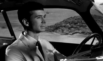 Movie still from “Phaedra” (1962), directed by Jules Dassin – A black and white photo of a man driving a car; Close Up shot, Low angle