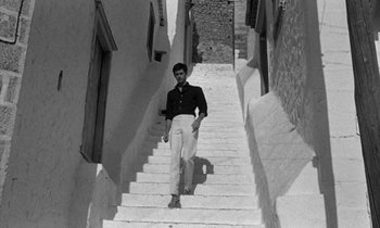 Movie still from “Phaedra” (1962), directed by Jules Dassin – A black and white photo of a man walking down a set of stairs; Wide shot, Low angle