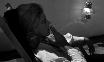 Movie still from “Phaedra” (1962), directed by Jules Dassin – A woman smoking a cigarette while sitting in a chair; Close Up shot, Low angle