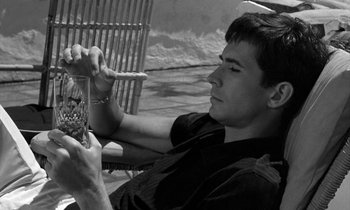 Movie still from “Phaedra” (1962), directed by Jules Dassin – A man sitting in a chair with a cigarette in his mouth; Close Up shot, Low angle