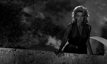 Movie still from “Phaedra” (1962), directed by Jules Dassin – A black and white photo of a woman leaning on a wall; Medium shot, Low angle