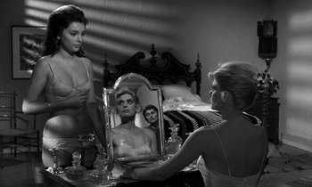 Movie still from “Phaedra” (1962), directed by Jules Dassin – A woman looking in a mirror while another woman looks on; Medium shot, Over the shoulder angle